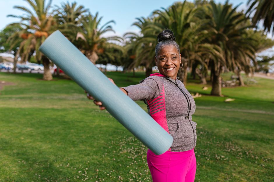Mujer adulta mayor activa y sonriente practicando yoga en la naturaleza